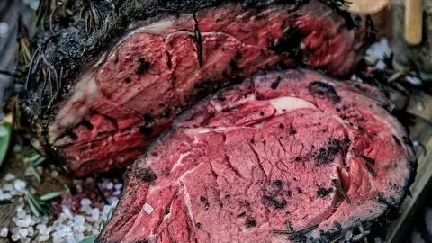 Juicy herb-crusted roast beef with rosemary and sea salt on a wooden board, perfect for gourmet dining.