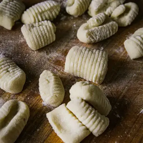 Fresh homemade gnocchi on a floured wooden surface, ready to cook for a delicious Italian meal.