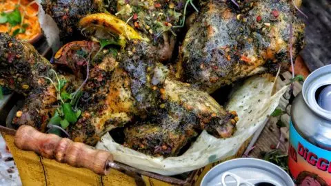 Spicy herb chicken wings with lemon in a rustic basket, paired with craft beer cans and an autumn leaf background.