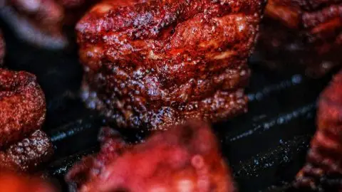 Close-up of smoked barbecue meat with a rich, glazed crust, highlighting delicious texture and savory aroma.