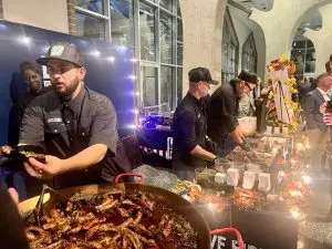 Chefs serve barbecue at decorated indoor event