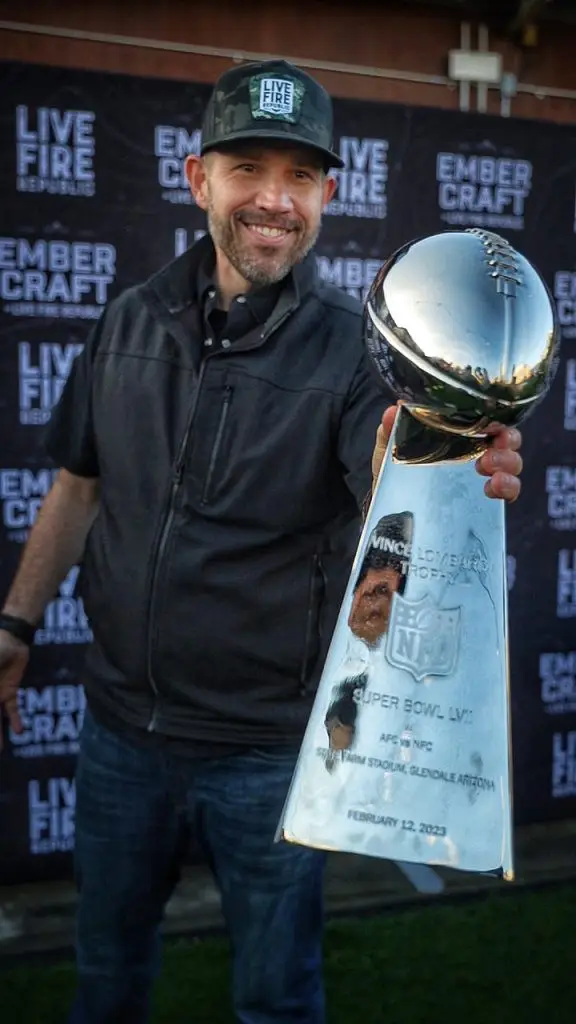 Man holds Vince Lombardi Trophy at outdoor event