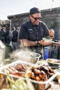 Man serving grilled food at outdoor gathering